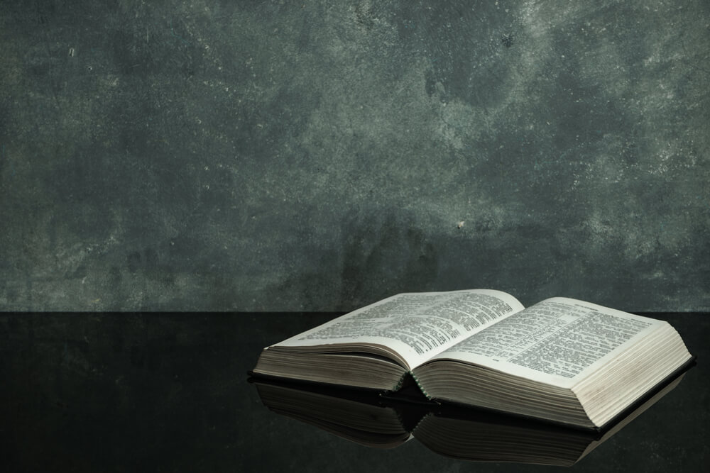Bible on a black glass table. Beautiful gray wall background