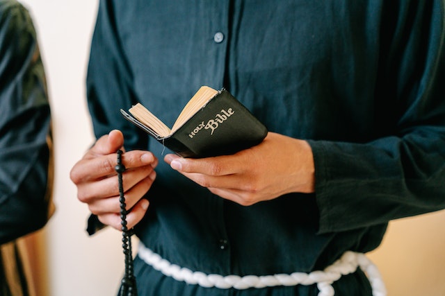 Close-up Photo of Person reading on Bible and holding a Rosary