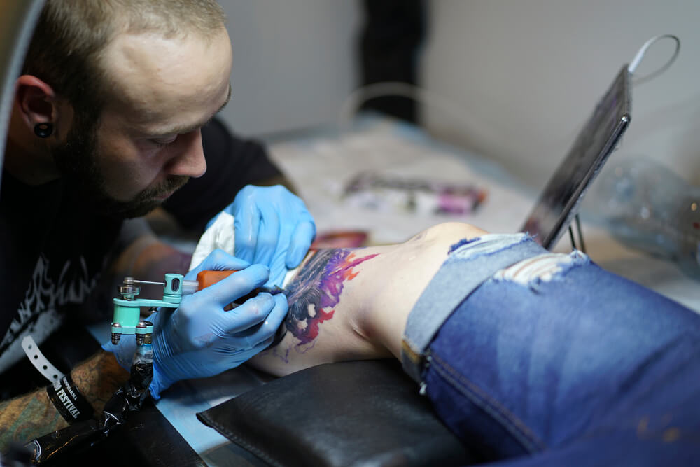 Tattoo artist while working on a leg tattoo