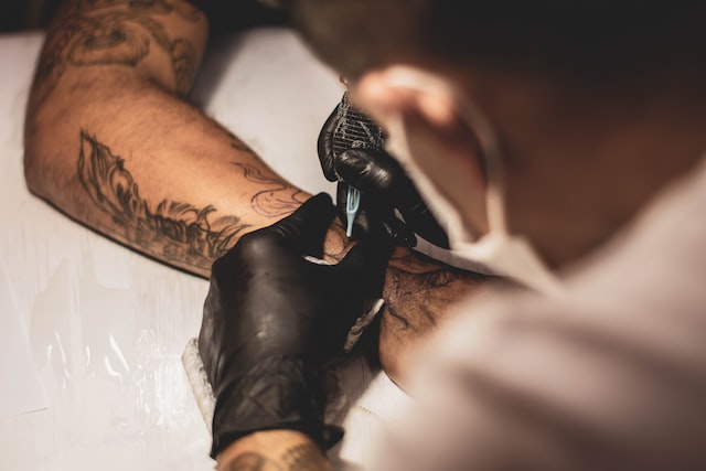 Tattoo artist while working on an arm tattoo
